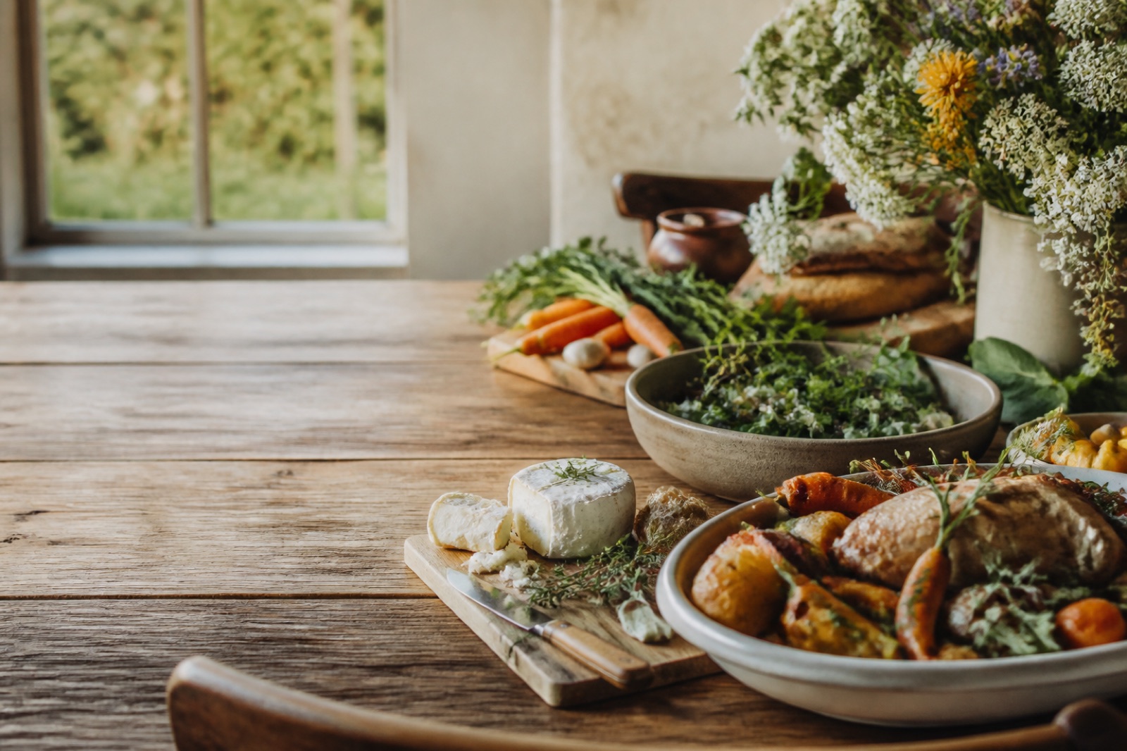 Artisan goat cheese and a prepared family dinner on a farmhouse table